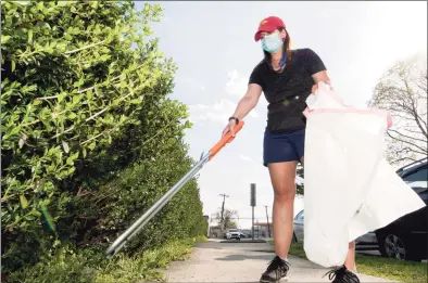  ?? Christian Abraham / Hearst Connecticu­t Media ?? Jessica Hanley picks up trash near her home along Shippan Avenue in Stamford on Tuesday. Hanley, a public school teacher in Greenwich, spends her weekends scavenging the streets for garbage on her Shippan Avenue block and trying to create a greener world, one discarded trash bag at a time.