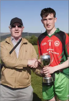  ??  ?? Schools Games Administra­tor Jim Murphy presents to cup to St Kevin’s captain Aaron Kennedy.