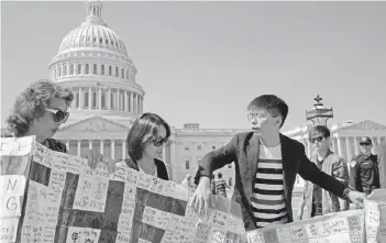  ?? — AFP photo ?? Wong (right) and other activists unfurl a banner containing messages, written during a rally outside the US consulate in Hong Kong.