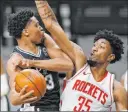  ?? Eric Gay The Associated Press ?? UNLV product Christian Wood pressures Spurs forward Keldon Johnson in the first half of the Rockets’ 109-105 win Thursday at the AT&T Center.