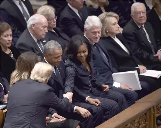  ?? BRENDAN SMIALOWSKI/AFP/GETTY IMAGES ?? President Donald Trump shakes hands with former first lady Michelle Obama as former presidents Barack Obama, Bill Clinton and Jimmy Carter and former first lady Hillary Clinton sit in their pew before the funeral service for former President George H.W. Bush on Wednesday at the National Cathedral.