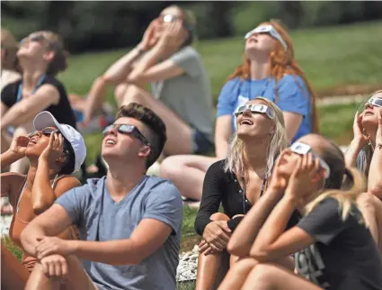  ?? KELLY WILKINSON/INDYSTAR ?? Students look at the peak of the solar eclipse, watching from the Butler campus outside Holcomb Observator­y, Aug. 21, 2017.