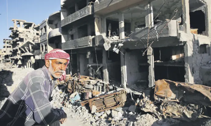  ??  ?? A Syrian man stands between buildings destroyed last summer in fighting between the U.S.-backed YPG and Daesh terrorists, in Raqqa, Syria, April 5.