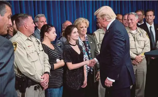  ?? [ FOTO AFP ] ?? Trump bersalaman dengan pegawai polis dan anggota keluarga mereka selepas berucap di ibu pejabat polis Metropolit­an di Las Vegas, kelmarin.