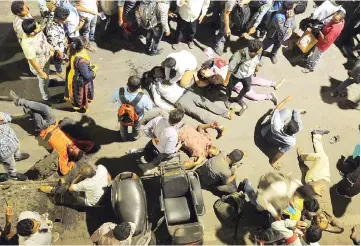  ?? — AFP photo ?? Onlookers gather around injured people.