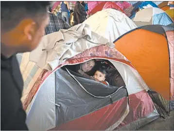 ?? GREGORY BULL/AP ?? Ruth Aracely Monroy looks out of a tent with her 10-month-old son, Joshua inside a migrants shelter in Tijuana, Mexico.