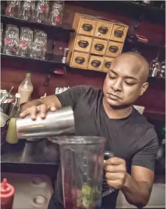  ??  ?? Raja Owusu-Ansah, owner of Republic Bar &amp; Grill prepares behind the counter the Kokroko, famous cocktail made from Sobolo and Akpeteshie, in Accra.