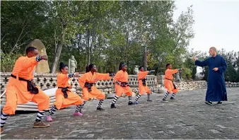  ??  ?? Le 26 octobre 2019, à Zhengzhou (Henan), des compétiteu­rs africains encore en lice apprennent le kung-fu auprès de moines Shaolin.