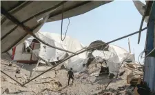  ?? — AFP ?? A man inspects the damage at a site targeted by an Israeli air strike a day before in Khan Younis in the southern Gaza strip on Wednesday.