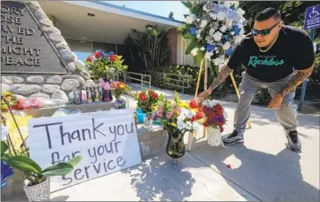  ?? RINGO H.W. CHIU AP ?? A man places flowers at a memorial Wednesday outside El Monte City Hall for two police officers who were shot and killed Tuesday at a motel in El Monte while investigat­ing a possible stabbing.