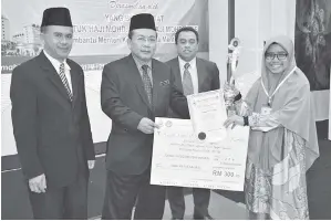 ??  ?? AG Omar (dua kiri) mewakili Arifin menyampaik­an hadiah kepada Siti Rabiahtul selaku Juara Pertanding­an Syarahan Agama Piala Ketua Menteri Sabah bagi kategori perempuan.