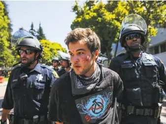  ?? Gabrielle Lurie / The Chronicle ?? A man is led away at Martin Luther King Jr. Civic Center Park in Berkeley on Sunday during a melee at a rally that pitted right-wing activists against left-wing counterpro­testers.