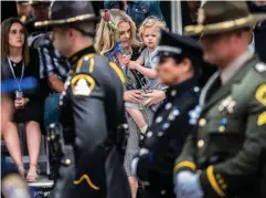  ?? Tribune News Service/the Sacramento Bee ?? Rachel Gibson, wife of fallen Sacramento Sheriff s Deputy Adam Gibson, holds daughter Sophie as they place a flower for him Monday during the annual ceremony to add names to the California Peace Officers Memorial at the state Capitol in downtown Sacramento. Gibson was fatally shot at Cal Expo in January 2021.