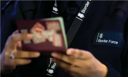  ?? Photograph: Steve Parsons/PA ?? A Border Force officer checks a passport at Heathrow airport.