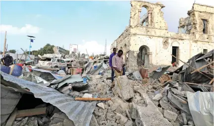  ??  ?? Civilians at the scene after a suicide car explosion in front of Doorbin hotel in Mogadishu, Somalia, on Saturday. (Reuters)