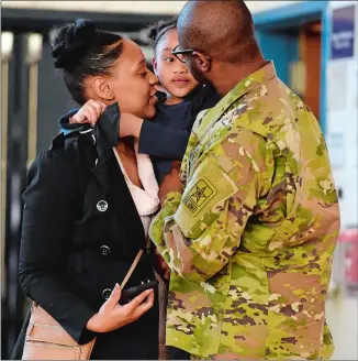  ?? SEAN D. ELLIOT/THE DAY ?? Camryn Almond, 5, gets hugs from her mother, Sade, left, and her father, U.S. Army Specialist Cleyce Almond, when he surprises her at school Thursday. Spec. Almond has been away from home at Army boot camp for nine weeks and arranged to surprise his...