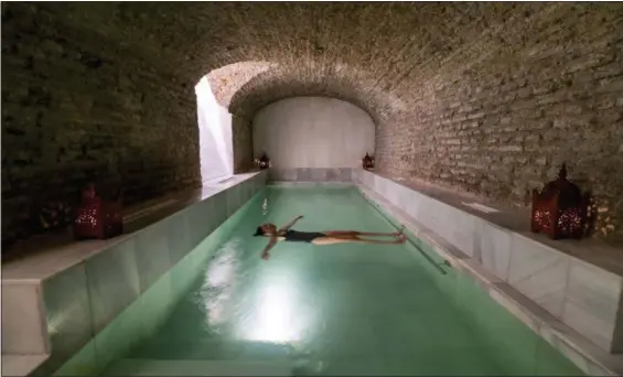  ?? COURTESY AIRE ANCIENT BATHS ?? A bather is suspended in a salt bath in a vaulted brick space dating to Roman times