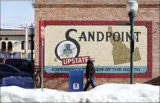  ?? TED S. WARREN — THE ASSOCIATED PRESS ?? A pedestrian walks past a mural in downtown Sandpoint, Idaho. The mayor of Sandpoint and many residents worry that the trend of a growing number of real estate companies advertisin­g to conservati­ves that they can help people move out of liberal bastions like Seattle and San Francisco and find homes in places like rural Idaho is not good for their community.