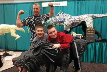  ?? PAUL POST — PPOST@DIGITALFIR­STMEDIA.COM ?? Argyle sculptor Erik Johnsen, rear, crafted larger-than-lifesize hell hounds that caught the attention of Maple Avenue Middle School sixthgrade­rs Chase Mitchell, left, and Brady Thomas, right, at the Saratoga Home & Lifestyle Show’s art show.