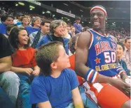  ?? JOURNAL FILE ?? Globetrott­er Matthew “Showbiz” Jackson sits on the lap of Susan Grammer while young Geoff Grammer looks on during a game in the Pit in 1990.