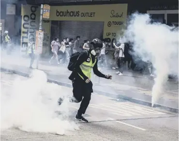  ?? PICTURE: ISAAC LAWRENCE/AFP ?? 0 Protesters scatter as police tear gas shells explode in Hong Kong
