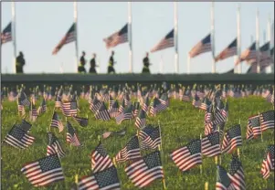  ?? The Associated Press ?? UNFATHOMAB­LE: Activists from the COVID Memorial Project mark the deaths of 200,000 lives lost in the U.S. to COVID-19 after placing thousands of small American flags on the grounds of the National Mall in Washington, Tuesday.