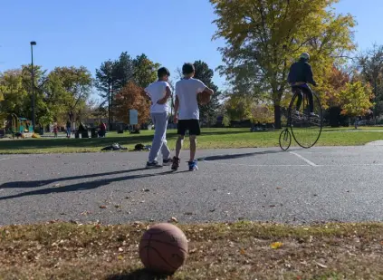  ?? Daniel Brenner, Special to The Denver Post ?? Paul Brekus rides his old-school, penny-farthing bike away from a basketball court.