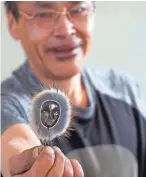  ?? TREVOR HUGHES/USA TODAY ?? Edwin Weyiouanna shows a carving made from mastodon ivory, whale baleen and rabbit fur. Many Shishmaref residents carve items to sell to tourists on the mainland.