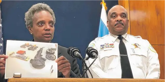  ?? FRAN SPIELMAN/SUN-TIMES ?? Mayor Lori Lightfoot on Tuesday holds up a photo of “custom automatic weapons” and a “drum magazine that can hold 200-plus bullets” seized in recent days from two offenders who “got a $10,000 bond.” She was wrong on several counts.