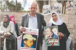  ?? — AFP ?? JERUSALEM: The father Hussein and mother Suha of Palestinia­n teenager Mohammed Abu Khdeir, who was killed last year, stand with posters of their son outside the district court yesterday.