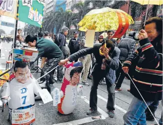  ?? Photo: REUTERS ?? Large-scale rally: Protesters carrying the symbol of the Occupy movement, yellow umbrellas, play with a roly-poly toy mocking Hong Kong chief executive Leung Chun-ying.