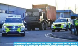  ??  ?? SALISBURY: Police officers escort an army truck, carrying a freight container laden with the car of Sergei Skripal, as it is driven from the Churchfiel­ds industrial estate in Salisbury, southern England as part of investigat­ions and operations in...