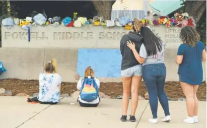  ?? Helen H. Richardson, The Denver Post ?? Youths pause to reflect at a makeshift memorial at Powell Middle School on Thursday. The memorial was set up for an eighth-grader who shot himself dead on the grounds of nearby Twain Elementary on Wednesday night. The death was the second student...