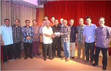  ??  ?? Masing (left) presents a mock cheque for RM1 million to Joseph Jinggut, who received it on behalf of SDNU Kapit for site clearing and earthworks of its new cemetery.