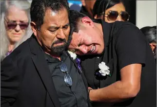  ?? ?? As a hearse leaves, Alejandro Lopez, left, and his son Giovanni Lopez-Ruano mourn the death of Giovanni's godfather, Marciano Martinez, after his funeral at Our Lady of the Pillar Catholic Church in Half Moon Bay.