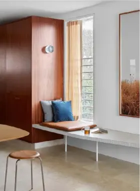  ??  ?? DINING (right) The Alhambra travertine used for the family-room plinth appears on much of the flooring, and the bench seat is edged in the same ceramic finger tiles. Anton Mini wall lamp, Volker Haug. LIVING (opposite) Design classics from the early 1960s include the vintage Fler ‘Narvik’ armchairs, a Cassina ‘Rio’ table from Mobilia and a vintage glass pendant light by Aloys Gangkofner for Peill & Pulitzer. Custom sofa by Ohlo Studio. Mattiazzi ‘Cugino’ side table, District. Minotti ‘Jacques’ green ottoman, Dedece. Gubi ‘9602’ floor lamp, designFARM. The walls throughout are Dulux Fair Bianca Quarter. All the window glass is low-emissivity (low-e) to reduce the intensity of UV rays and heat.