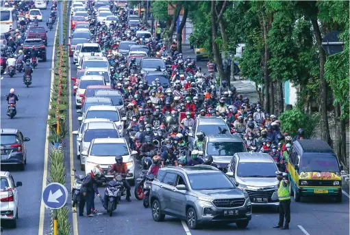  ?? ALFIAN RIZAL/JAWA POS ?? TERSENDAT KARENA LAKA: Pengendara motor tersenggol mobil ketika melintas di Jalan Wonokromo kemarin (14/1). Insiden seperti ini kerap menjadi pemicu kemacetan.