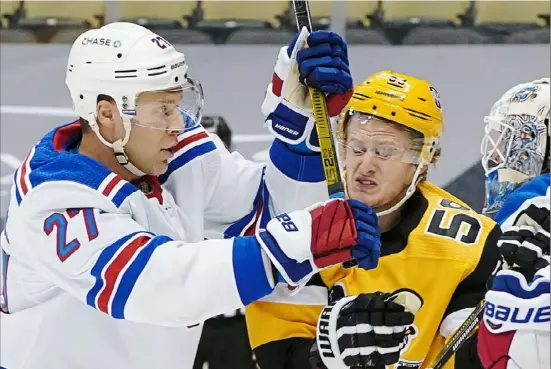  ?? Peter Diana/Post-Gazette photos ?? Jake Guentzel, right, absorbs a blow from New York’s Jack Johnson Tuesday night at PPG Paints Arena.