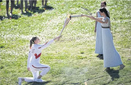  ?? AFP ?? Torchbeare­r Anna Korakaki, Greece’s Rio 2016 gold medallist in the 25m pistol shooting, receives the Olympic flame during the lighting ceremony in ancient Olympia.