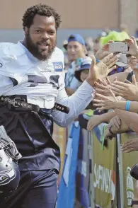  ?? AP PHOTO ?? AFTER COMMUNICAT­ION: Michael Bennett greets Seattle fans at the start of this year’s training camp in Renton, Wash.