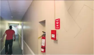  ?? COLLEEN DE NEVE/ CALGARY HERALD ?? A resident walks down the hall past one of the swastikas and racist graffiti that have been written on the hallway walls of the apartment block at 1419 17th Ave NW.