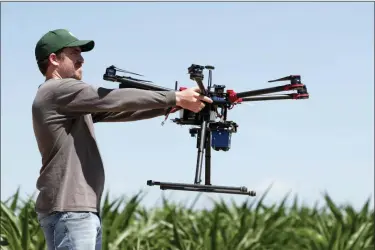  ?? DAVID ZALUBOWSKI — THE ASSOCIATED PRESS ?? In this Thursday photograph, United States Department of Agricultur­e intern Alex Olsen prepares to place down a drone at a research farm northeast of Greeley, Colo. Researcher­s are using drones carrying imaging cameras over the fields in conjunctio­n with stationary sensors connected to the internet to chart the growth of crops in an effort to integrate new technology into the age-old skill of farming.