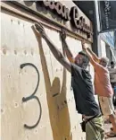  ?? AKIL J. SIMMONS/AP ?? People board up a store Wednesday in preparatio­n for Category 3 Hurricane Humberto in Hamilton, Bermuda.