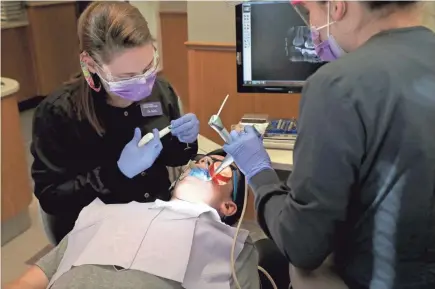  ?? MICHAEL SEARS / MILWAUKEE JOURNAL SENTINEL ?? Katharine Nelson Suwalski (left) fills a cavity for Warren Bauer, 13, with the help of McKenna O’Hearn, a dental assistant, at the Waukesha clinic of Waukesha County Community Dental Clinics.