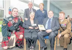  ??  ?? Special moment Margaret McLauchlin (seated) collects her brother’s medal