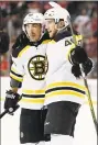  ?? Kathy Willens / Associated Press ?? Bruins center Brad Marchand, left, and defenseman Matt Grzelcyk celebrate Grzelcyk’s goal during the first period against the Devils Tuesday.