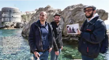  ??  ?? A tourist holds a picture of a ‘Game of Thrones’ (GoT) scene to fans from Spain, on March 28, during a guided visit, under the Lovrijenac Fort.