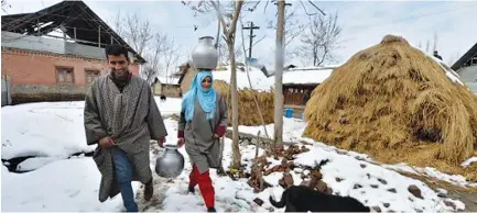  ??  ?? KASHMIRIS carry water utensils filled from a water tanker on the outskirts of Srinagar on Jan. 19. The icy temperatur­es have frozen many bodies of water in Kashmir as well as drinking water taps.