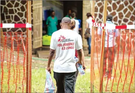  ?? JUNIOR KANNAH/AFP ?? Doctors Without Borders team members walk through an Ebola security zone at the entrance of the Wangata Reference Hospital in Mbandaka, Democratic Republic of Congo, on Sunday.