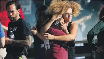  ?? AP ?? Trader Joe’s employees hug after Los Angeles police escorted them out of the supermarke­t where a gunman kept people hostage for three hours